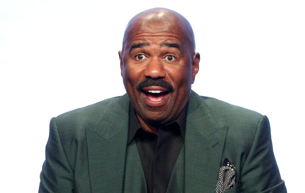 Steve Harvey smiling in a green suit