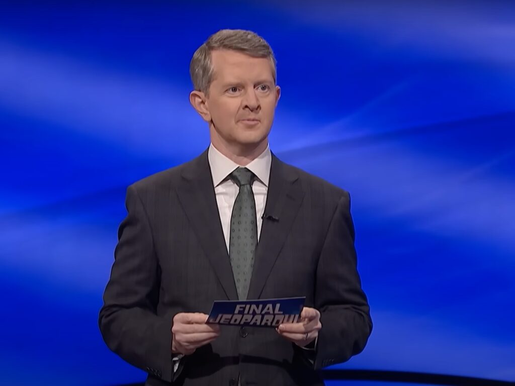 screenshot of Ken Jennings hosting Jeopardy! in a gray suit